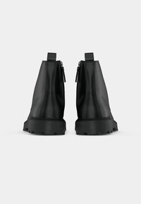 Černé kotníkové boty vyrobené z hladké kůže, s uzávěry na zip, kontrastními texturovanými gumovými podrážkami a poutky na patě.