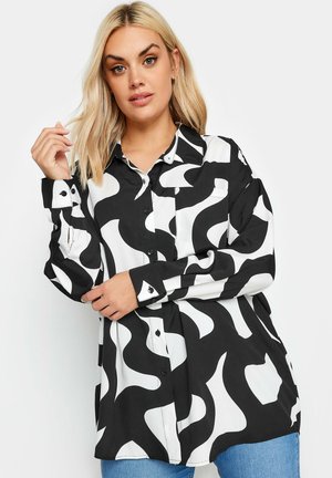 Camicia button-up bianca e nera con un motivo a onde, maniche lunghe e vestibilità ampia. Presenta colletto e bottoni neri sui polsini.