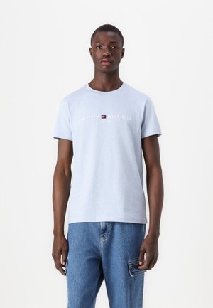 Tricou din bumbac de culoare bleu deschis, cu guler rotund, mâneci scurte și text brodat alb care spune "TOMMY HILFIGER EST. 1985" pe față.