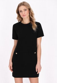 Rochie neagră tricotată cu mâneci scurte, decolteu rotund, două buzunare frontale cu butoane aurii, material texturat, lungime deasupra genunchiului.
