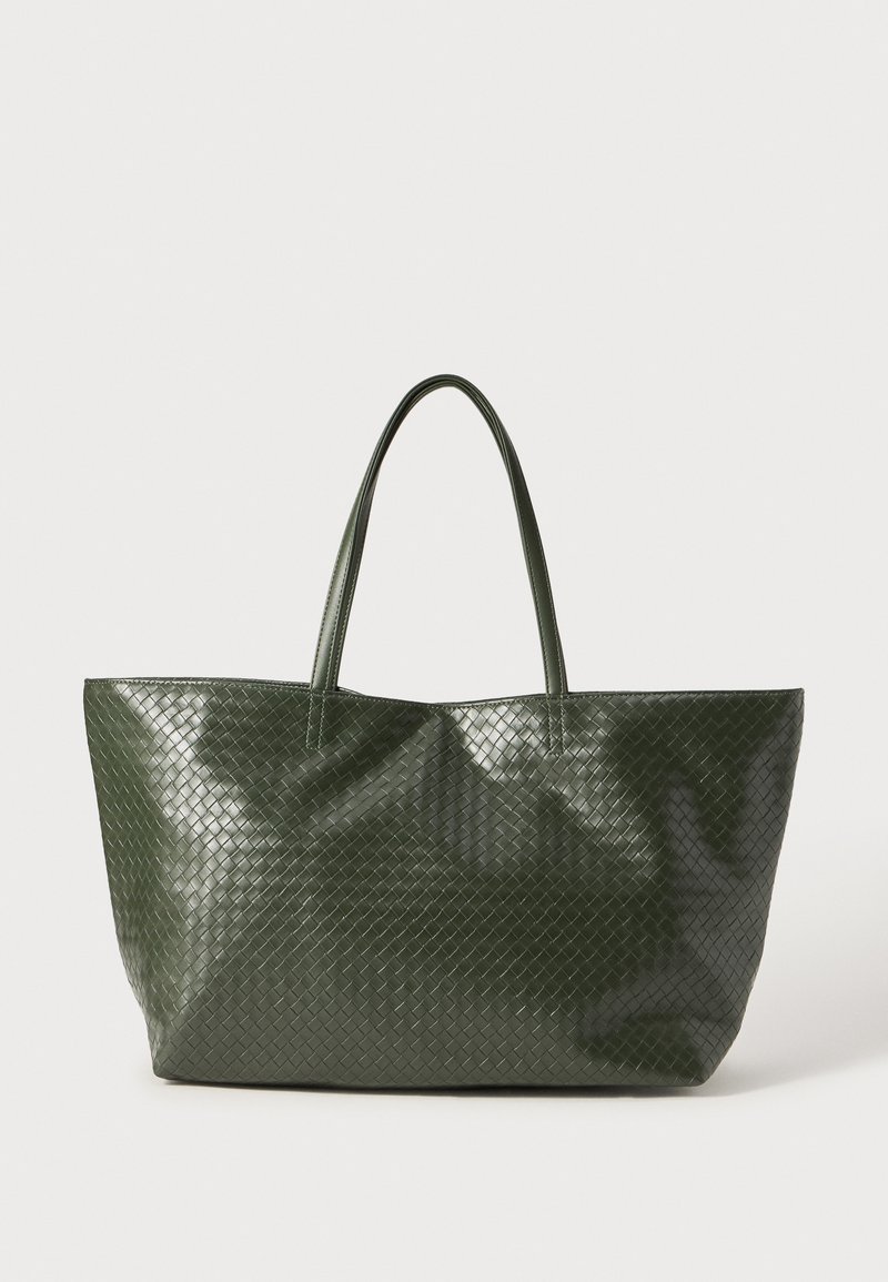 Green woven tote bag with a glossy finish, featuring two sturdy handles and a spacious design. Textured pattern across the surface.