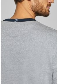 T-shirt en coton gris avec un col rond agrémenté d'accents bleu marine, affichant une texture lisse et un design minimaliste.