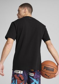 Sort bomuld t-shirt med korteærmer, med et lille logo på ryggen, paired med farverige mønstrede basketballshorts og en basketball.
