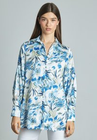 Blusa de manga larga en tejido ligero con estampado floral en azul y verde, cierre delantero de botones y un corte relajado.