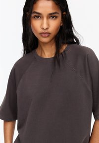 Donkergrijze sweatshirt met korte mouwen, raglanmouwen en een ronde hals. Gemaakt van een zachte, gestructureerde stof, met minimale stikseldetails.