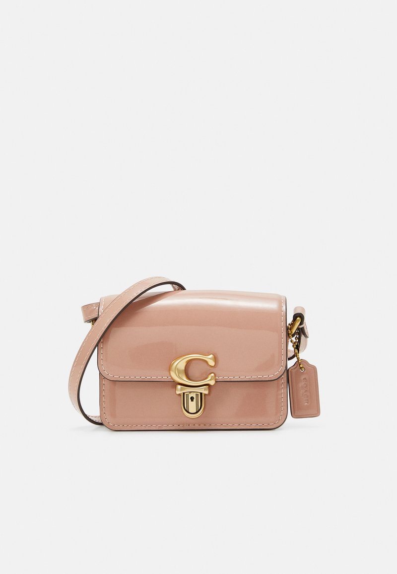 Lille pink patentlæder crossbody taske med guld hardware, en buet klap, signaturlogo og justérbar skulderrem. Har en aftagelig mærkat.