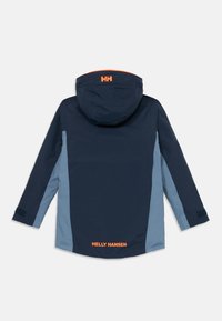 Nepremokavá bunda s tmavomodrým telom, svetlomodrými bočnými panelmi a oranžovým logom na kapucni a chrbte, s nastaviteľnými manžetami.