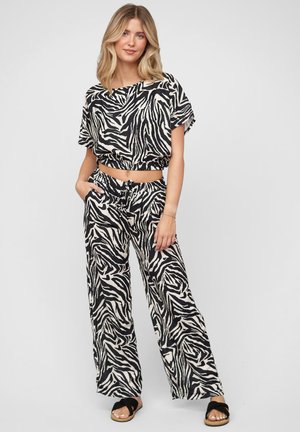 Zebraprint tweedelig outfit bestaande uit een cropped top en wijde broek in zwart en beiger. Lichtgewicht stof met een ontspannen pasvorm en elastische tailleband.
