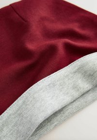 Bordowy materiał o miękkiej fakturze, z szarym wykończeniem. Projekt jest gładki i rozłożony, ukazując kontrast kolorów i ścieg.