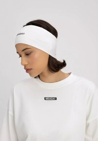 Biała opaska na głowę o gładkiej teksturze, z czarnym logo. W komplecie z białą bluzą, na której znajduje się podobne logo.