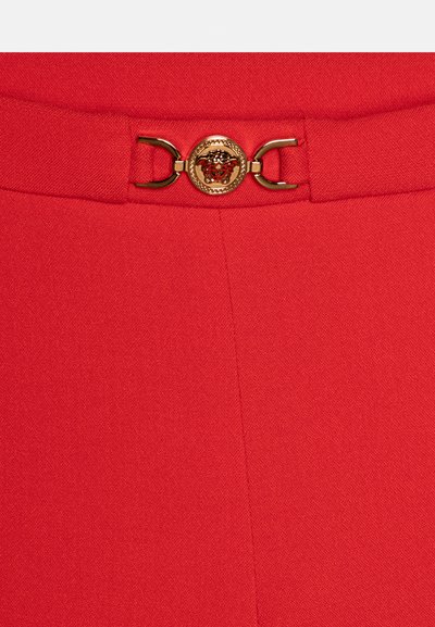 Tissu rouge avec une boucle décorative dorée ornée d'un emblème détaillé de tête de Méduse au centre d'une ceinture.