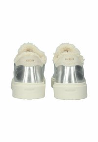 Zapatillas metálicas plateadas con un cuello esponjoso de color crema, que presentan un logo en relieve en la parte trasera y una suela blanca gruesa.