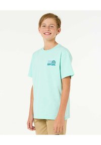 Camiseta de algodón verde menta con mangas cortas, que presenta un pequeño logo azul y blanco de "RIPCURL" en la parte izquierda del pecho.