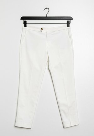 White trousers made of lightweight fabric, featuring a front button closure, two side pockets, and a slim fit design. Hangs on a black hook.