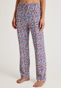 Bloemmotief pyjamabroek in het wit, met een patroon van rode en blauwe bloemen, elastische tailleband en een losse, rechte pasvorm.