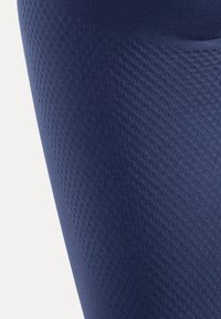 Marineblauw beenstof met een gestructureerde, patroonachtige afwerking. Materiaal lijkt rekbaar en aansluitend te zijn, ontworpen voor comfort en bewegingsvrijheid.