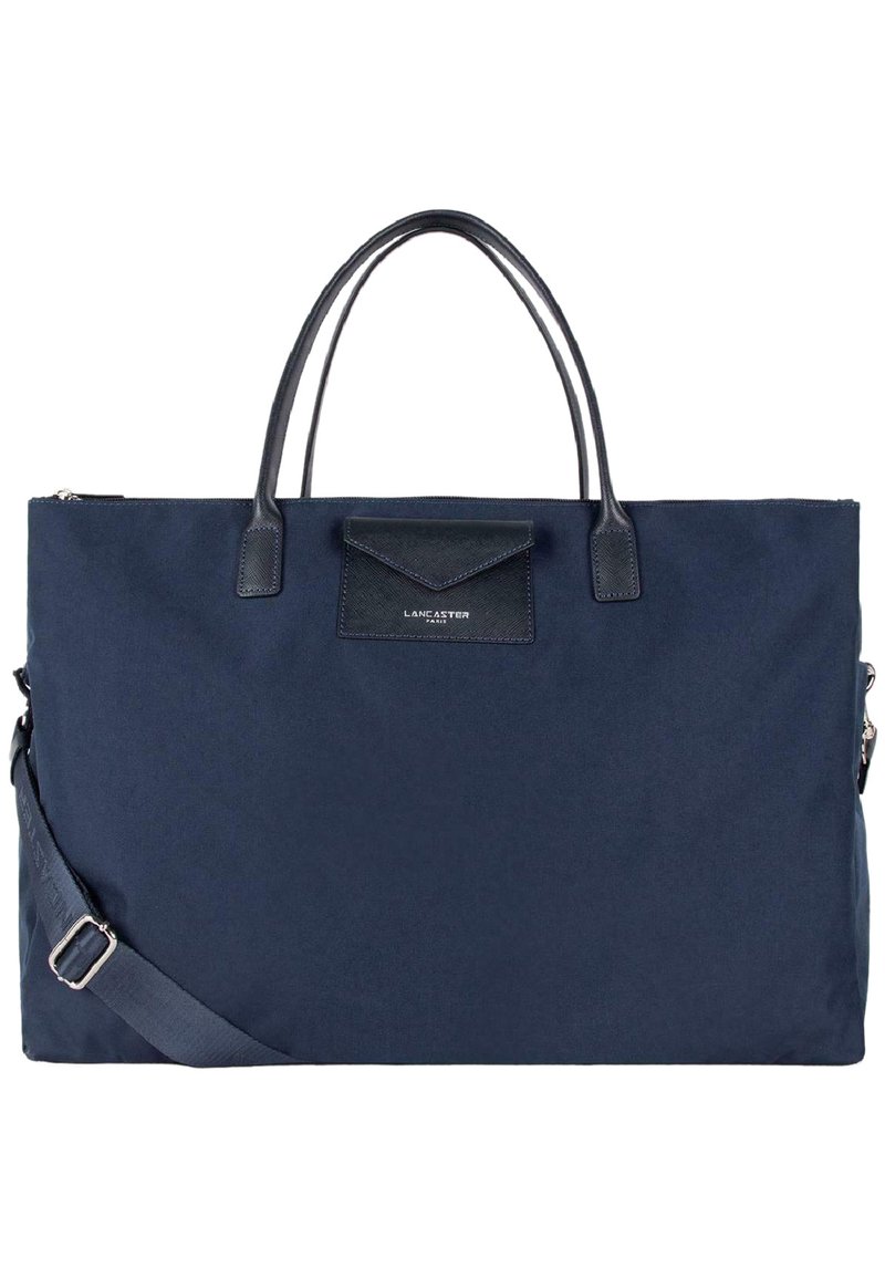 Borsa in tessuto blu navy con dettagli in pelle, manici doppi e una tracolla rimovibile. Presenta una tasca frontale e chiusura con zip.