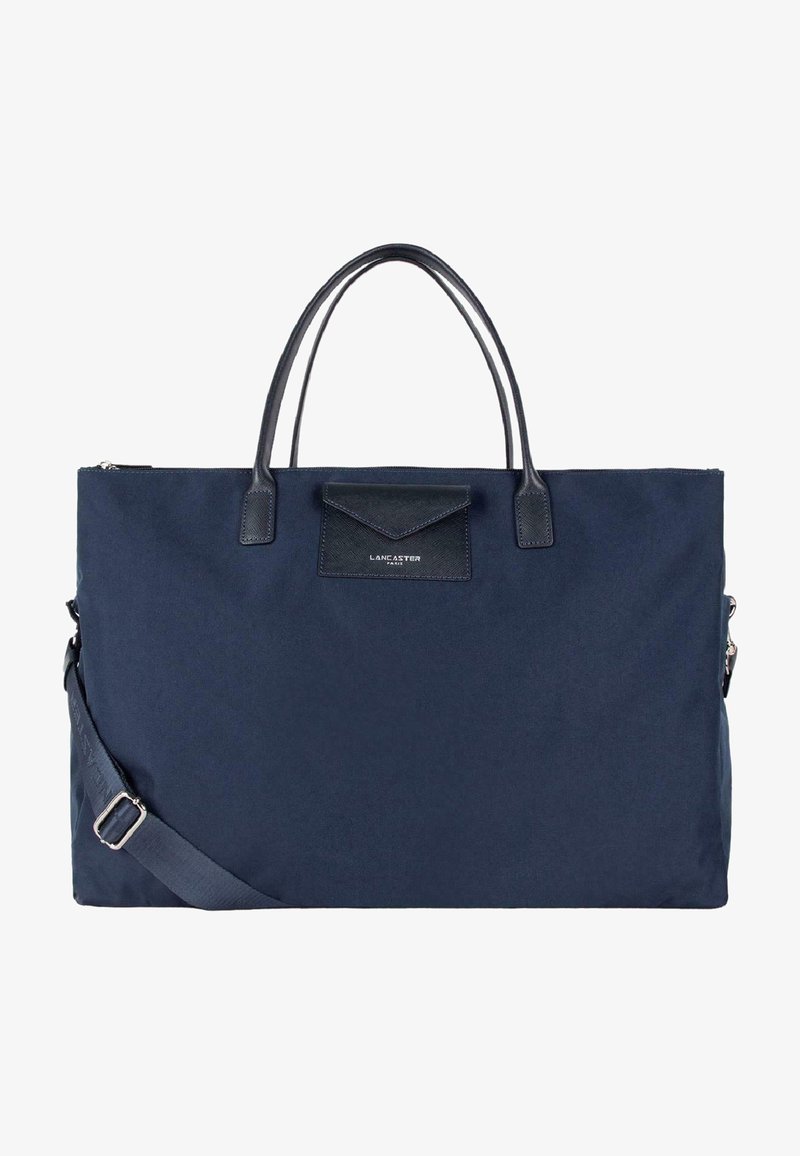 Borsa in tessuto blu navy con dettagli in pelle, manici doppi e una tracolla rimovibile. Presenta una tasca frontale e chiusura con zip.