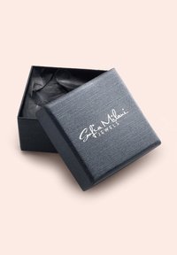 Svart texturerad smyckeslåda med en silverlogotyp "Sofia Milani Jewels" på locket, innehållande svart silkespapper inuti.
