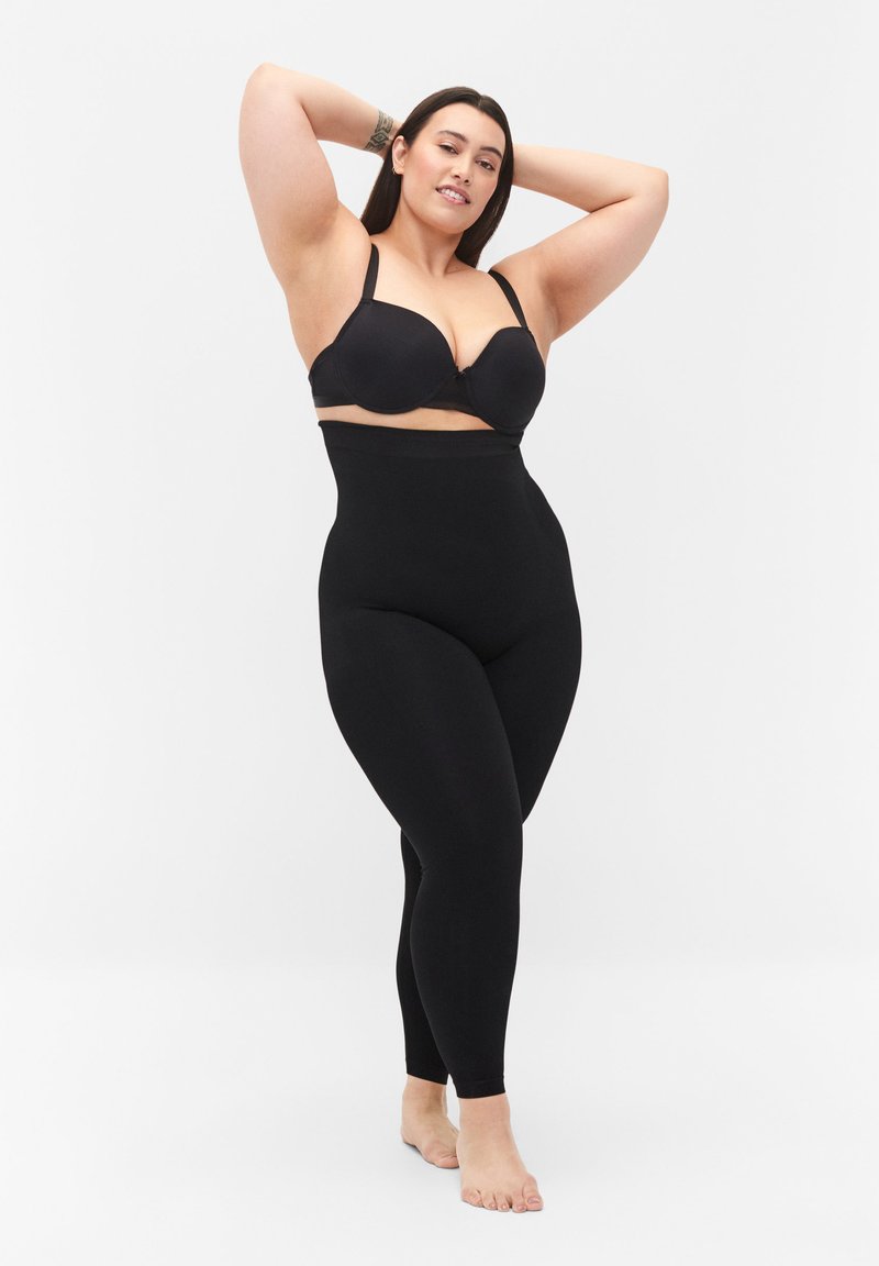 Soutien-gorge noir avec armatures et leggings noirs taille haute, tissu lisse, design ajusté, matériau extensible, finition mate, matériel minimal.