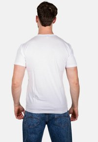 T-shirt bianco in cotone con maniche corte e scollatura rotonda, abbinato a jeans di denim blu. Texture liscia, senza motivi o dettagli visibili.