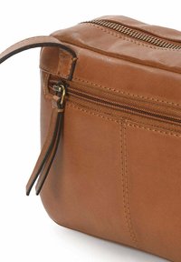 Bolso de cuero marrón con una textura suave, que presenta un cierre de cremallera y una pequeña correa lateral. Los acentos incluyen costuras finas y una cremallera metálica.