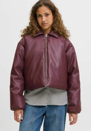 Bordeaux faux læder cropped jakke med frontlynlås, store ærmer og spids krave, lagdelt over en ternet skjorte.