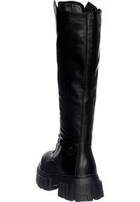 Bota negra hasta la rodilla, hecha de cuero suave, con una suela gruesa y con relieve, que presenta un diseño de cordones y una lengüeta en la parte posterior.