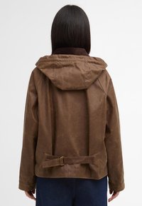 Brown waxed cotton jacket with a hood, textured surface, adjustable waist belt, and contrasting corduroy collar. Back view.
