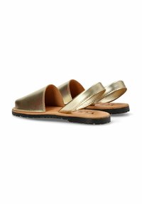 Sandalias deslizantes de color dorado metálico con dos correas anchas, una plantilla de cuero natural y una suela exterior de goma negra texturizada.