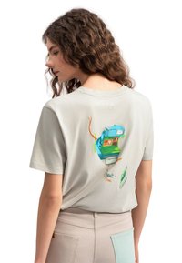 Lichtgrijs katoenen t-shirt met een kleurrijk grafisch ontwerp op de achterkant, dat een blauwe vendingmachine en abstracte elementen afgebeeldt.