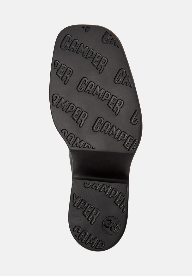 Suela de zapato de goma negra con el logotipo "CAMPER" elevado y la talla "38" grabada, con una textura suave y forma redondeada.