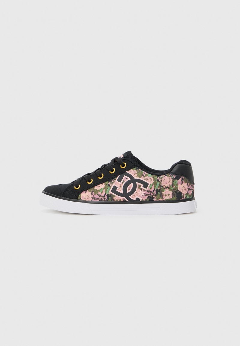 Zapatillas de deporte de caña baja con una base de lienzo negro, un patrón floral con rosas rosas y una suela de goma blanca. Ojetes dorados realzan el diseño.