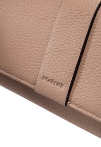 Torba iz svetlo rjave usnje z teksturirano površino, ki ima gladek panel in vtisnjen napis "MAÎTRE". Diskretne šivane podrobnosti ob robovih.