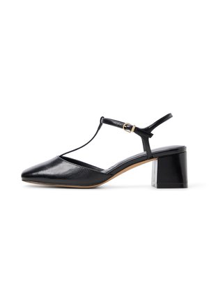 Zapato de cuero negro con tacón bajo de bloque, punta en forma de pico, tirante en T y hebilla dorada sobre fondo blanco.