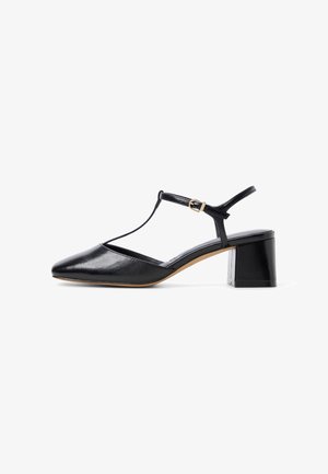Schwarzer Lederschuh mit niedrigem Blockabsatz, spitzer Schuhspitze, T-Riemen und goldener Schnalle auf weißem Hintergrund.