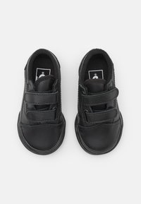 Chaussures en cuir noir avec deux bandes Velcro ajustables, forme de pointe arrondie, surface texturée et doublure intérieure douce.