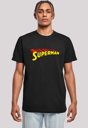 Juodas medvilninis marškinėliai su dideliu raudonu ir geltonu "SUPERMAN" logotipu kreivai išdėstytame, trumpomis rankovėmis ir apvaliu iškirpimu.