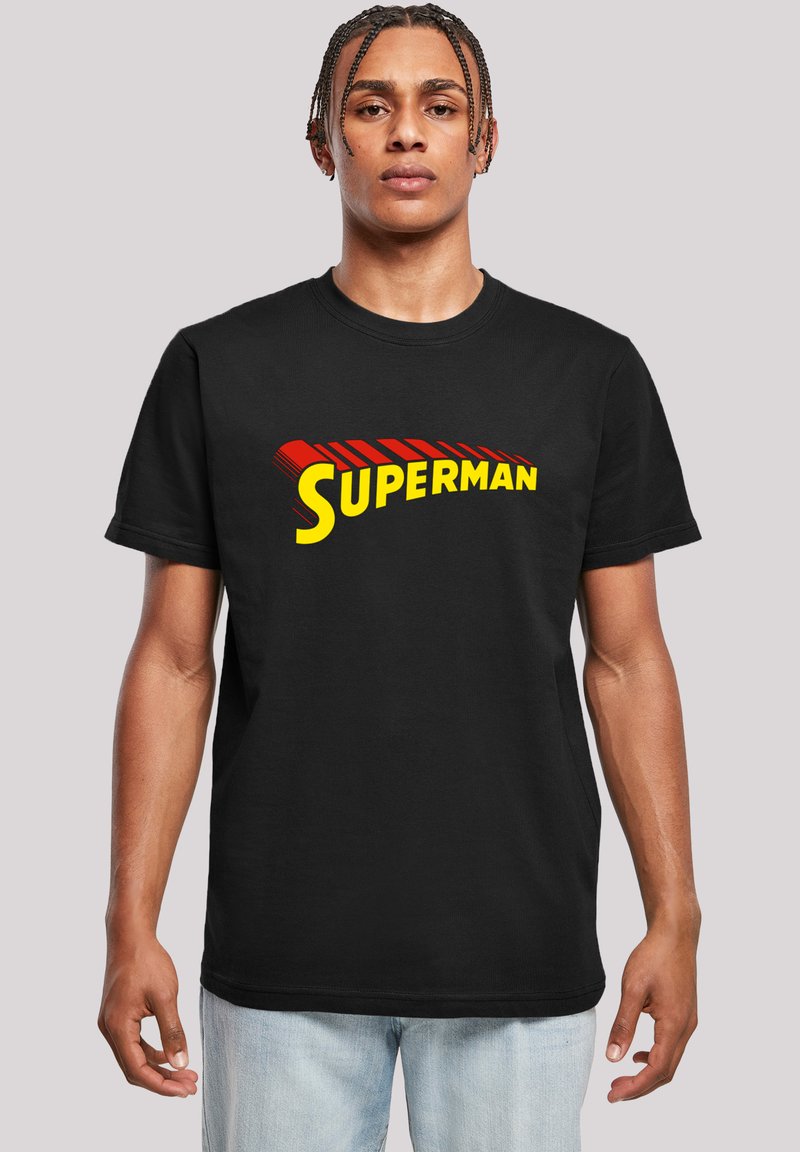 Juodas medvilninis marškinėliai su dideliu raudonu ir geltonu "SUPERMAN" logotipu kreivai išdėstytame, trumpomis rankovėmis ir apvaliu iškirpimu.