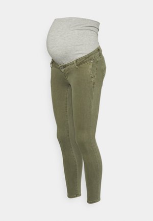 Jean skinny de maternité vert olive avec un panneau en tissu gris extensible sur le ventre pour le confort pendant la grossesse.