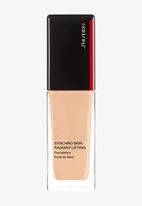 Shiseido Synchro Skin Radiant Lifting foundation in een heldere glazen fles met een zwarte dop en rode accent, met een gladde vloeibare textuur.