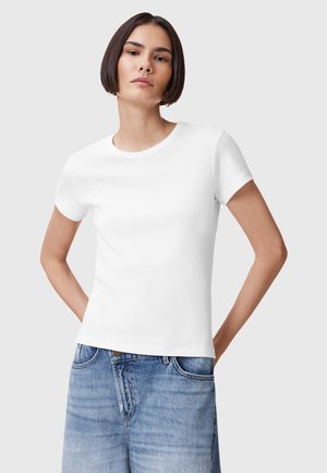 T-shirt bianco in cotone con maniche corte, colletto rotondo, design tailoring e texture liscia, abbinato a pantaloni shorts in denim azzurro chiaro.