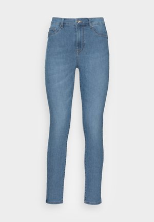 Jeans skinny en denim bleu clair, affichant une taille haute, des poches avant et une fermeture à glissière avec un bouton. Texture lisse avec des coutures minimales.