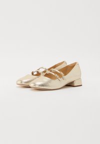 Goldfarbene, metallisch schimmernde Flat-Schuhe mit einem niedrigen Blockabsatz, ausgestattet mit zwei dekorativen Riemen und einer abgerundeten Spitze. Texturierte Oberfläche mit glatter Verarbeitung.