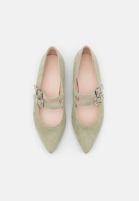 Ballerines en suédine verte de type Mary Jane avec deux brides à boucle en argent, bout pointu et doublure intérieure lisse.
