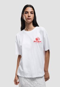 Witte katoenen t-shirt met korte mouwen, ronde hals, voorzien van een rode grafische print met de tekst "New York Lover Club."
