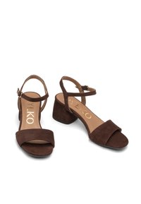 Sandali in suede marrone con tacco, cinturini alla caviglia, punta aperta e tacco quadrato. Presentano un design minimalista con una texture morbida.