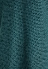 Tissu tricoté turquoise avec un motif en nid d'abeille texturé et une subtile ombre, montrant un tissage détaillé et un tombé doux.