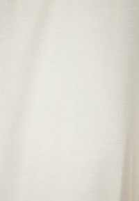 Ljus beige tyg med en slät textur, som visar en subtil lyster och fin väv. Inga synliga mönster eller dekorationer.