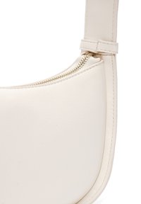 Borsa a spalla in pelle crema con texture liscia, forma curva e dettaglio in metallo dorato lungo la parte superiore per una chiusura sicura.